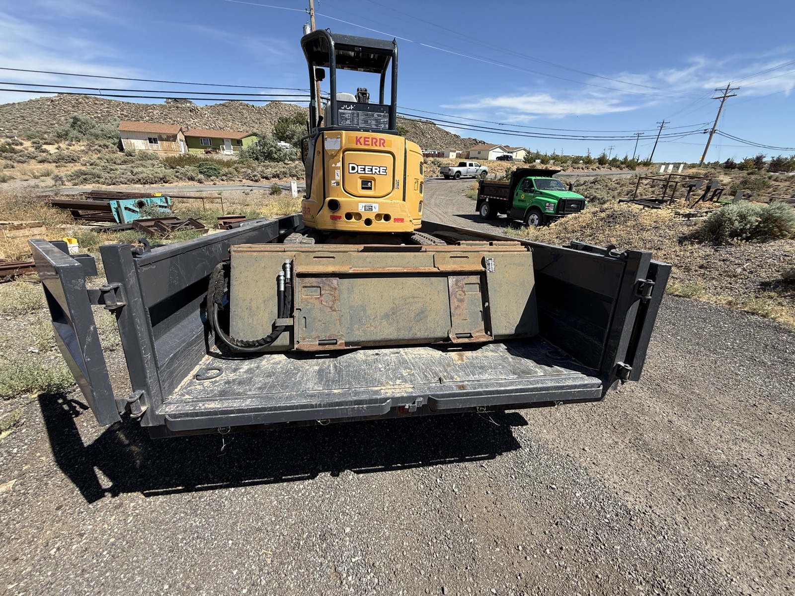 John Deere mini excavator with KERR lettering loaded on a dump trailer on a dry August day