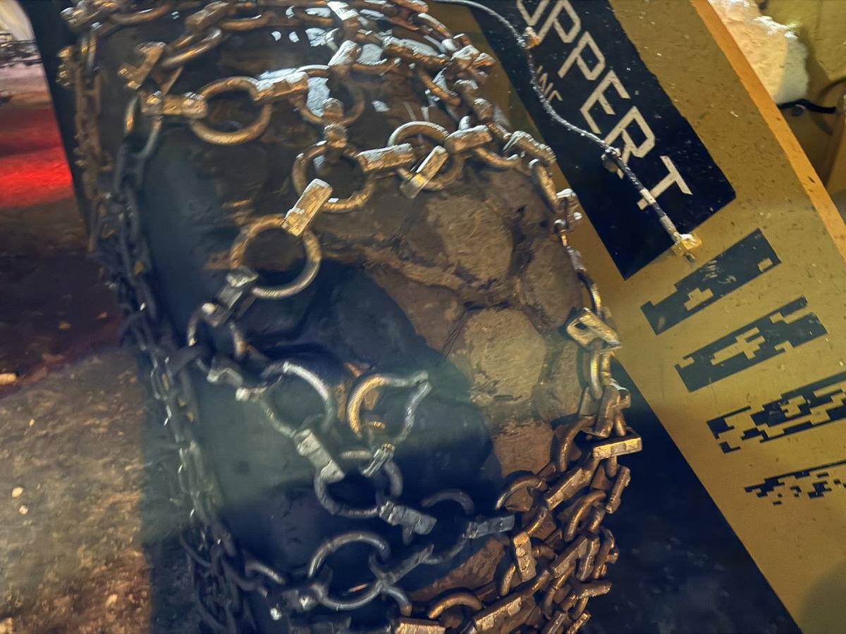 Close-up of heavy tire chains on a loader tire beside a Ruppert Inc. plow blade