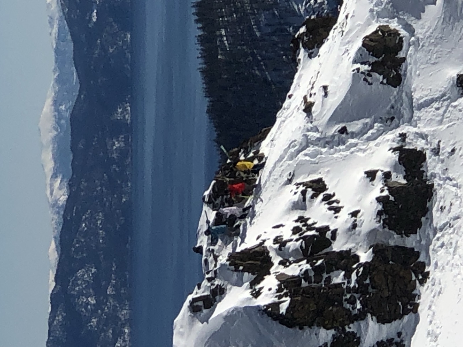 Skiers carrying their gear up a rocky ridgeline high above Lake Tahoe