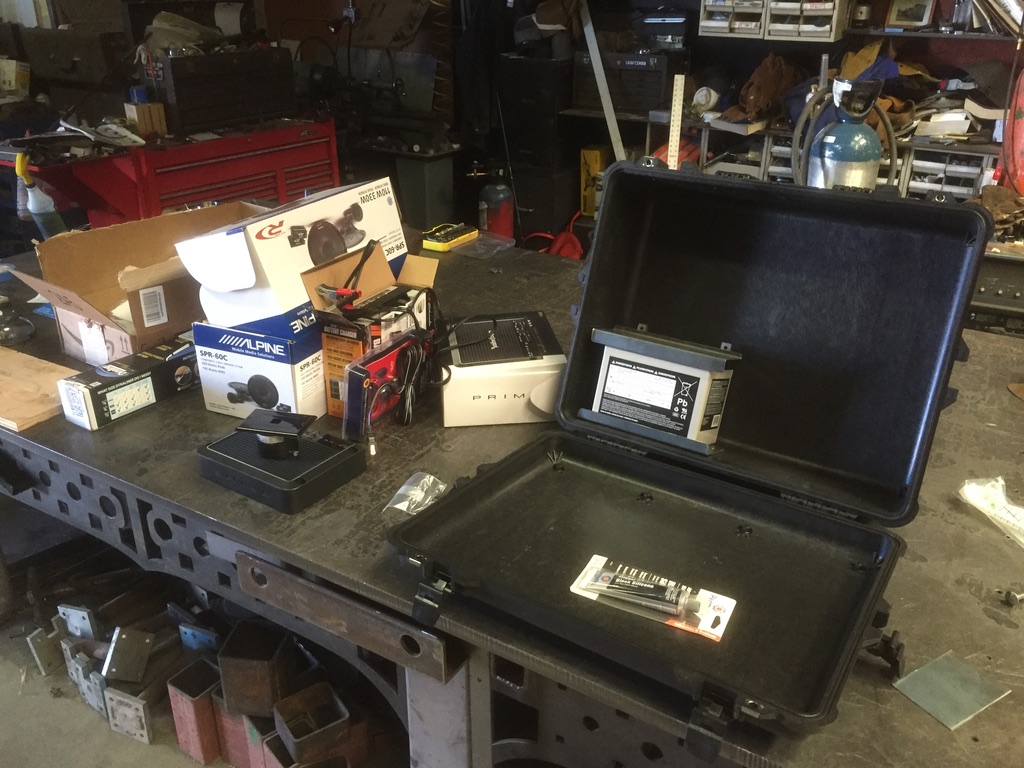 Pelican case, Alpine speakers, Rockford Fosgate amp, AGM battery, charger laid out on welding bench