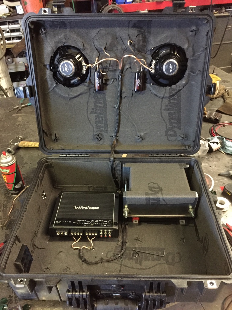 Pelican case open showing speakers in lid and amp + battery in case body, fully wired