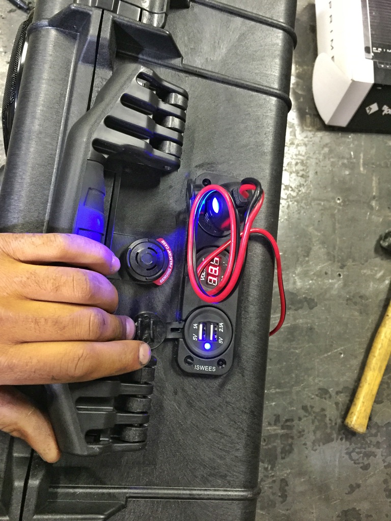 Hand holding boom box showing digital DC voltmeter and dual USB charging port lit blue