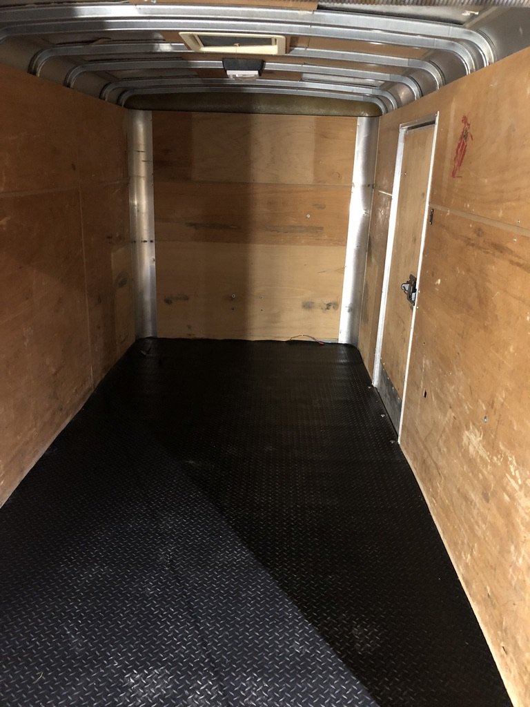 Second-angle view of the empty trailer interior showing the side man-door and front bulkhead