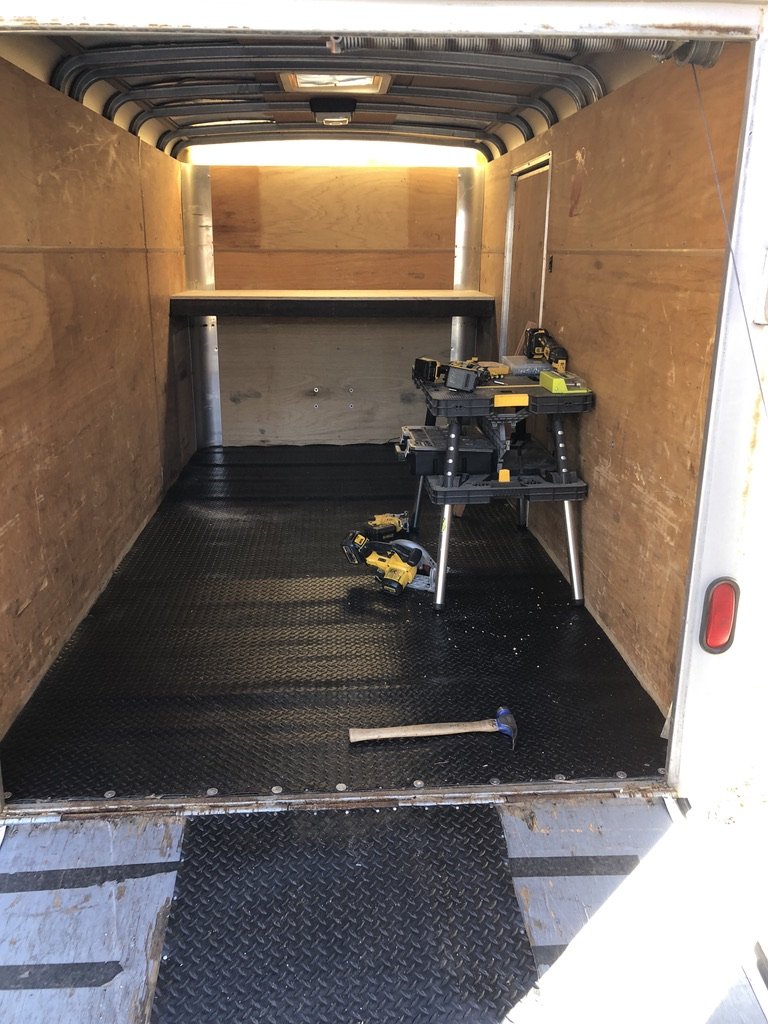Empty trailer interior in daylight, showing the thin plywood walls and factory dome light