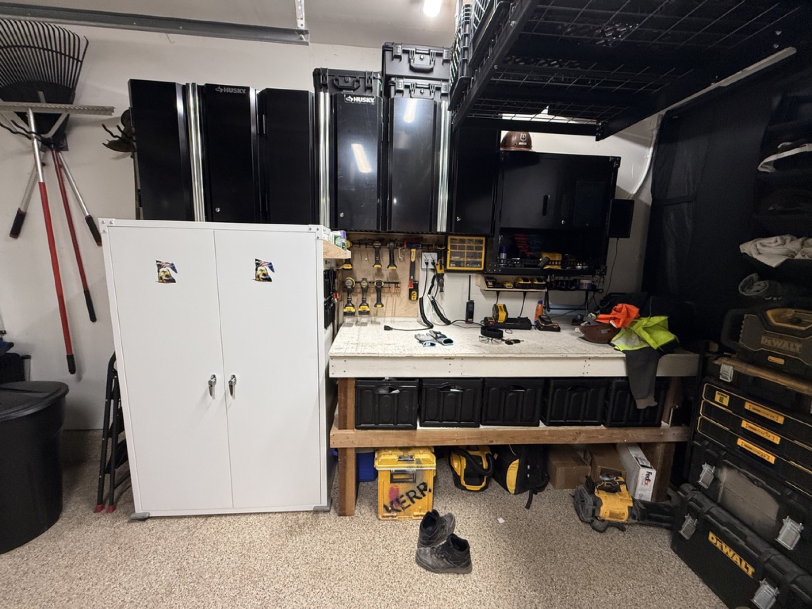 Wide view of the finished tool wall — Husky cabinets, white storage cabinet, workbench with totes, DeWalt stack
