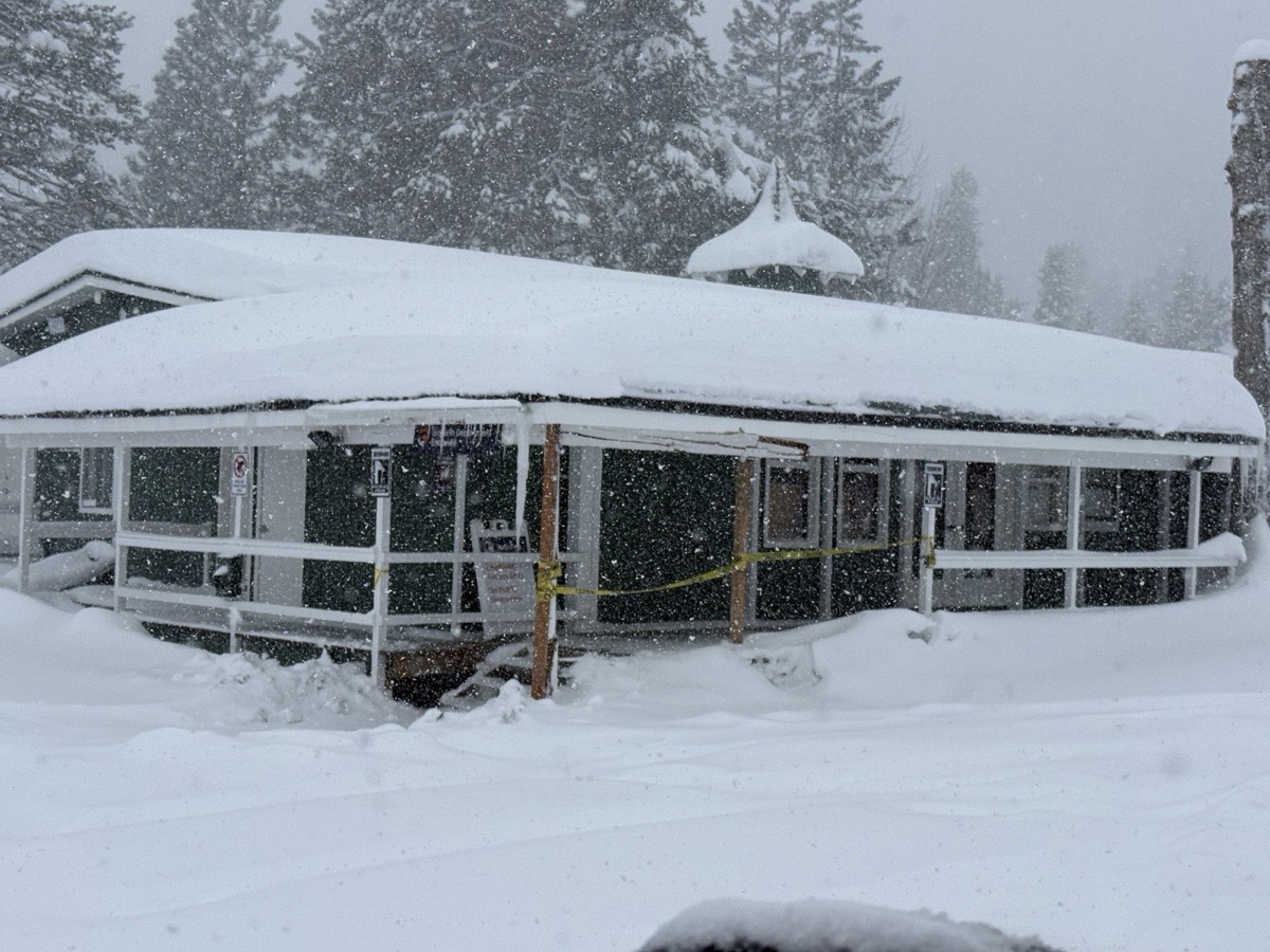 Snow-buried building at Palisades Tahoe Village with caution tape during heavy snowfall