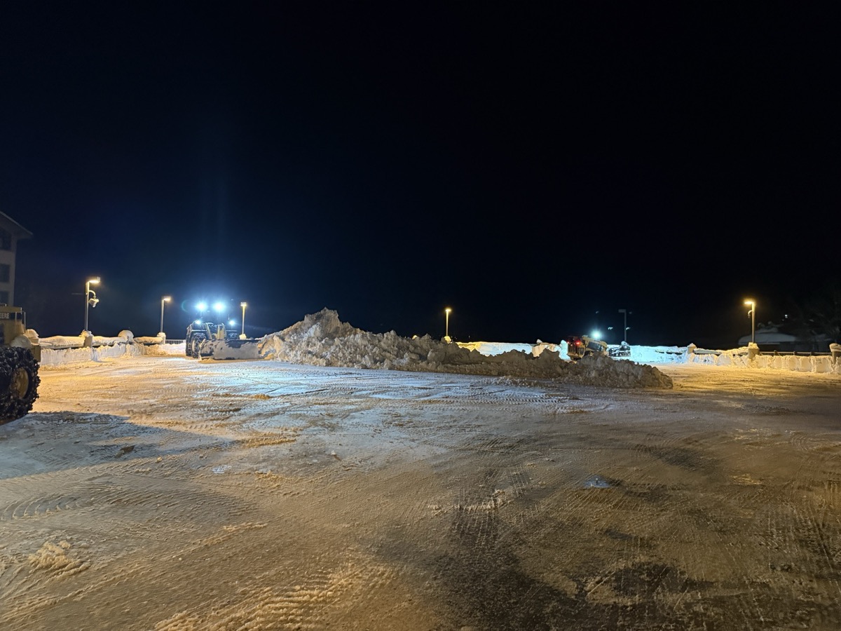 Cleared parking lot at night at Palisades Tahoe Village with snow piles pushed to the edges