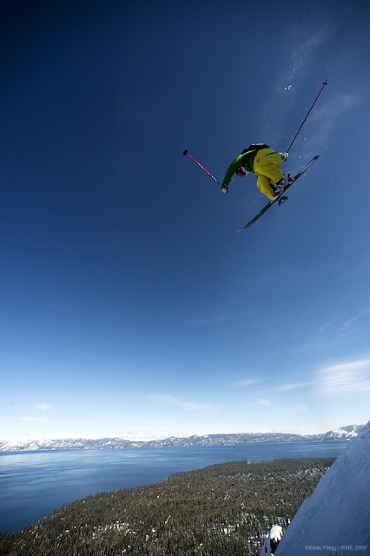 Errol launching a massive aerial above Lake Tahoe with blue sky and snow-covered mountains below