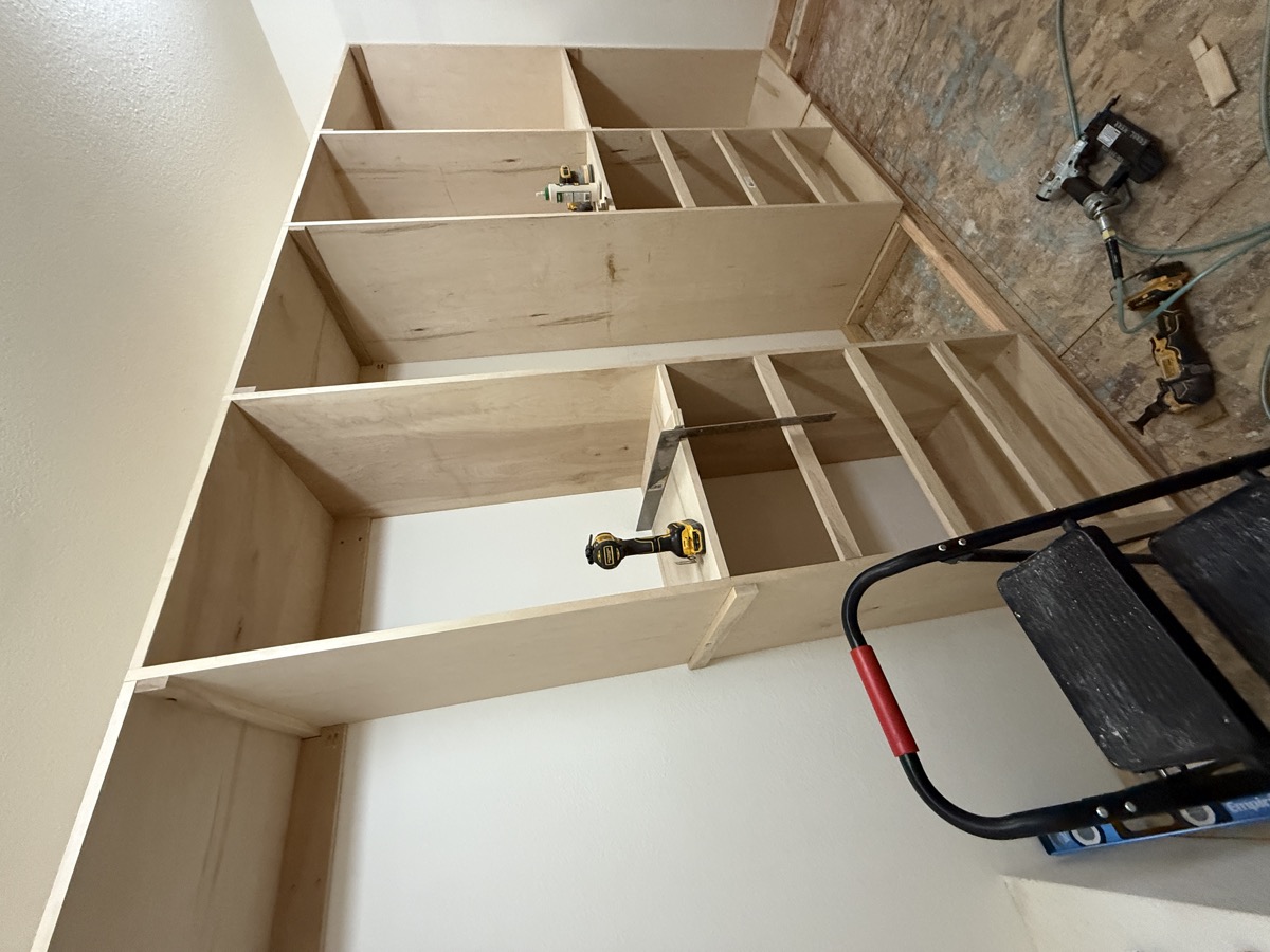 Final walk-in closet with custom plywood built-ins filling the eave space