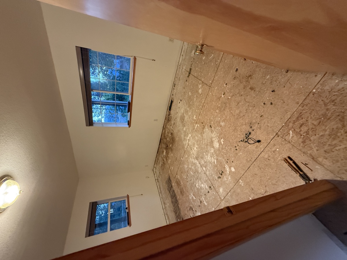 Empty bedroom with bare OSB subfloor before hardwood installation