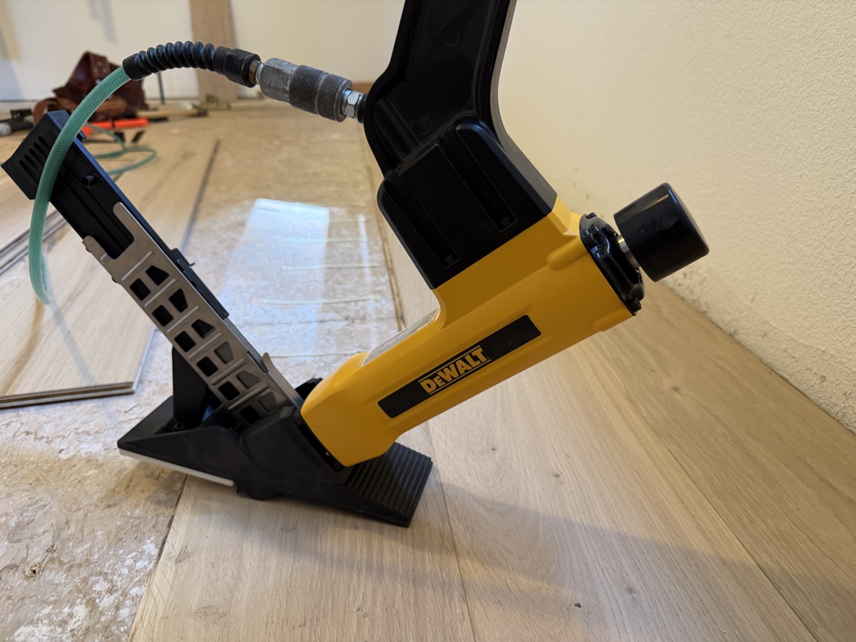 DeWalt flooring cleat nailer seated on a hardwood board tongue