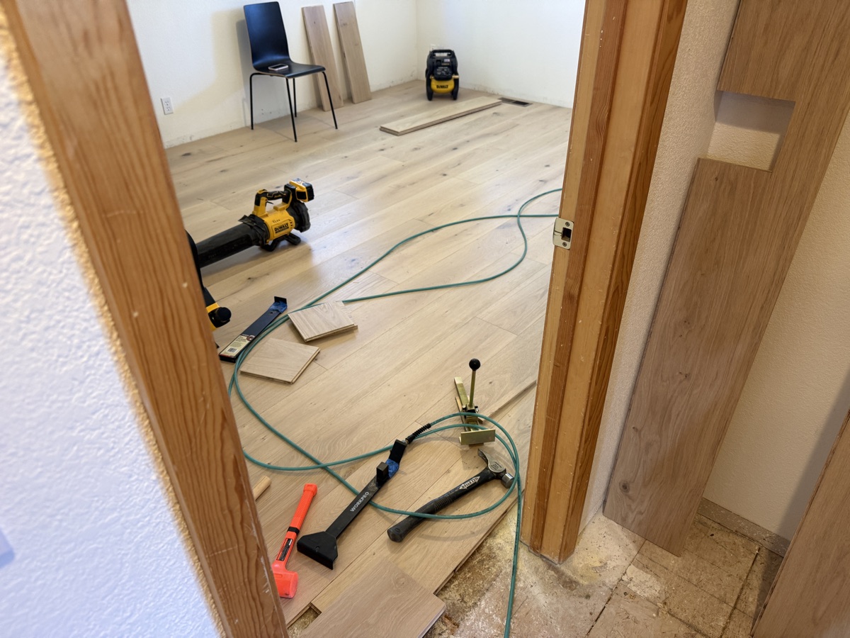 Hardwood floor viewed through oak-trimmed doorway showing room-to-hallway transition
