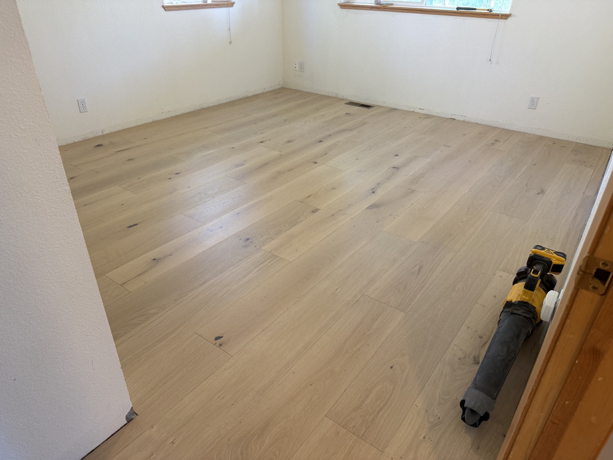 Nearly finished hardwood floor with last rows going in along the wall
