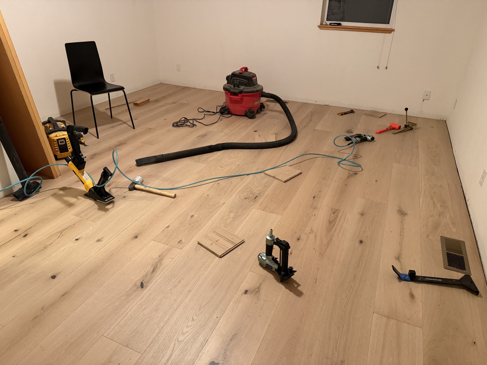 Near-complete wide-plank white oak floor with flooring nailers and tools