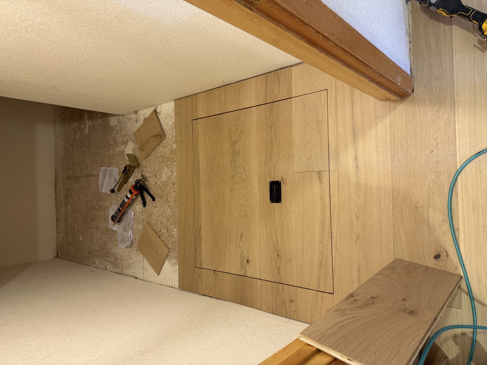 Hardwood floor installation showing custom access panel cut-out and transition to subfloor