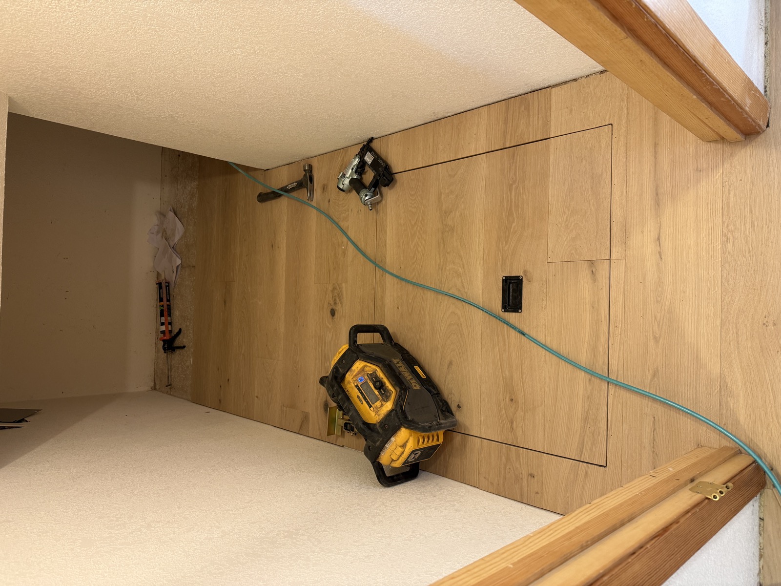 Near-complete hardwood floor installation with access panel cleanly integrated