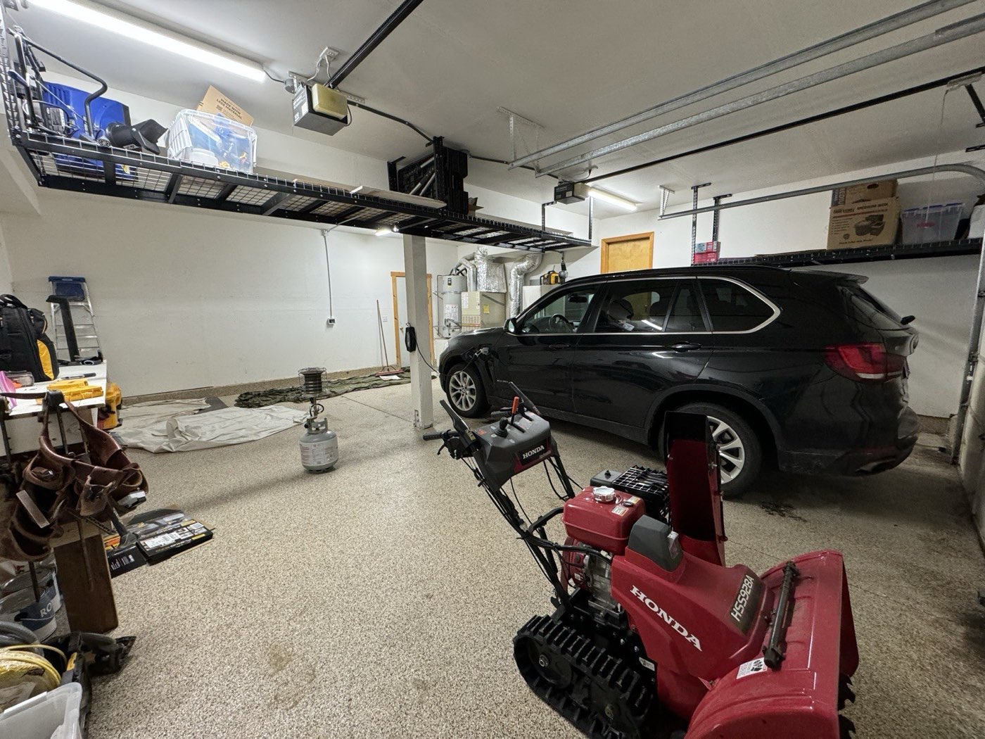 BMW parked in garage with overhead ski and general storage visible